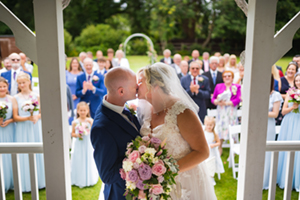 bride and groom kissing with people in the background