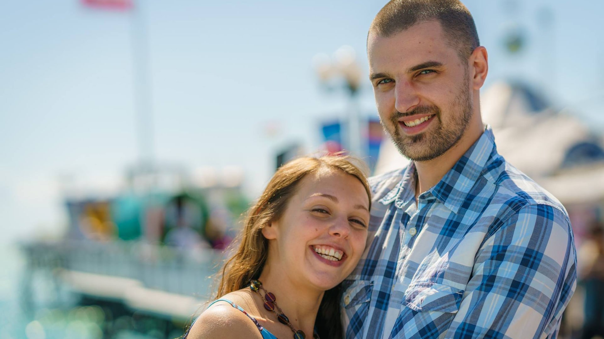 couple smiling in fron of brighton pier fair ground