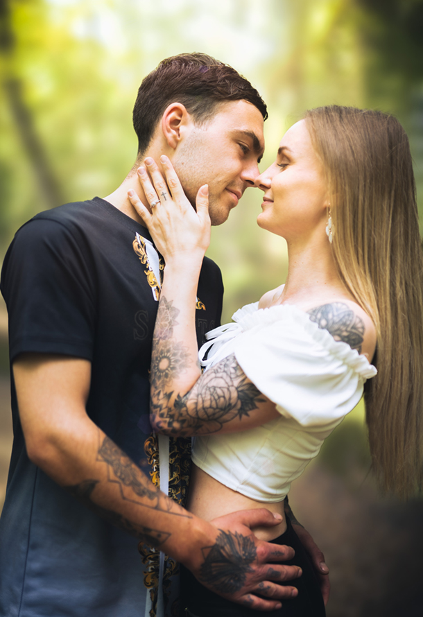 an engaged couple embrace in a woodland area