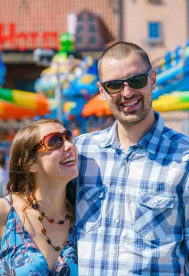 a couple looking happy with a fairground in the background